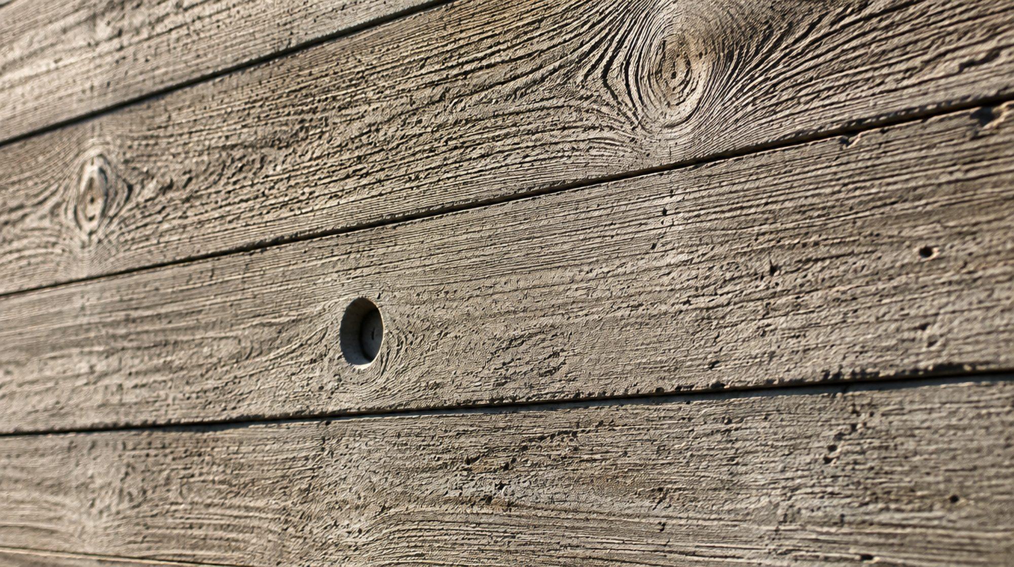 Macro detail of board-formed concrete showing timber grain and a recessed snap-tie hole.