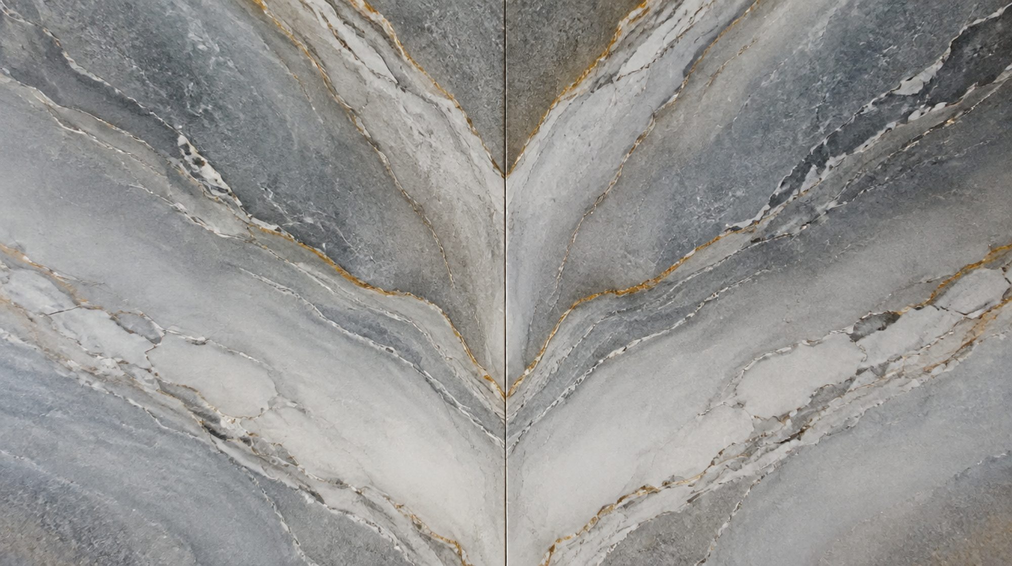 Macro detail of a book-matched marble seam, the two mirrored veins meeting in a hairline joint.